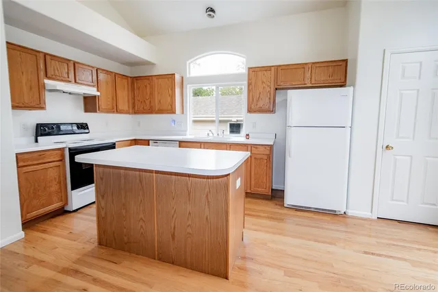 a kitchen with stainless steel appliances granite countertop a sink a stove a refrigerator cabinets and wooden floor