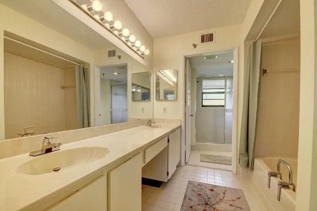a spacious bathroom with a tub sink and mirror