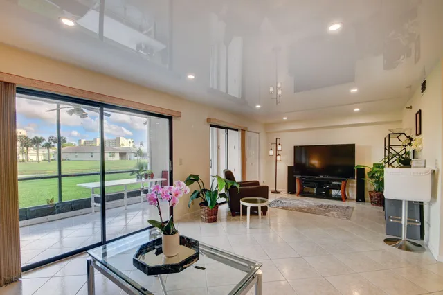 a living room with furniture a flat screen tv and a floor to ceiling window