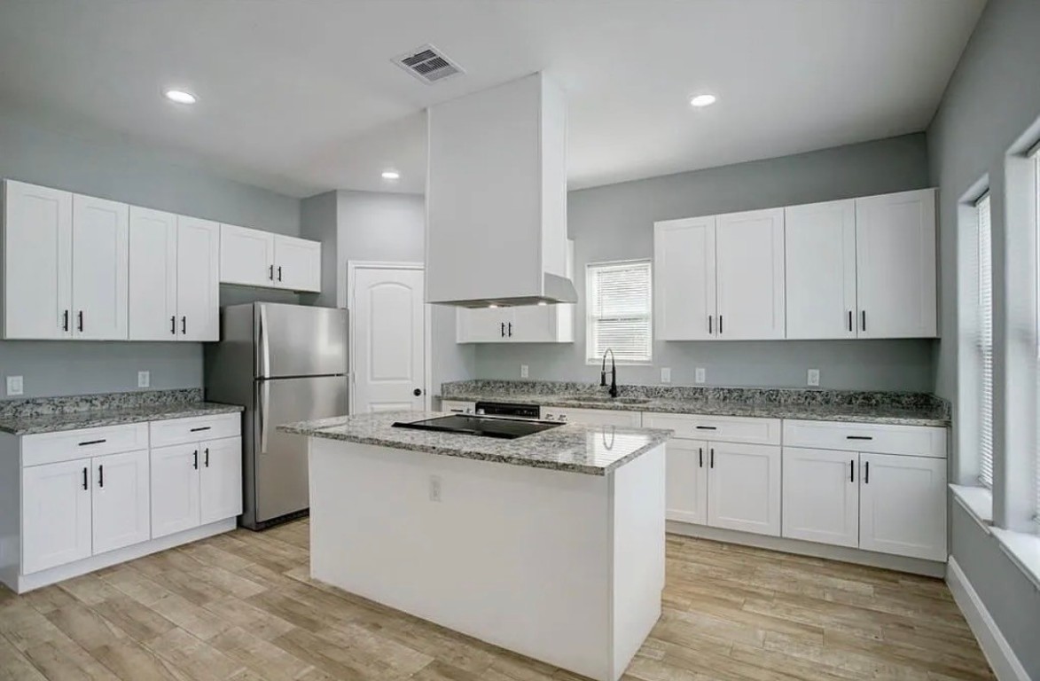 5754 Reed Road, Unit B Houston, TX 77033 - Photo 14 of 15 a kitchen with stainless steel appliances granite countertop a stove top oven a sink a refrigerator and white cabinets