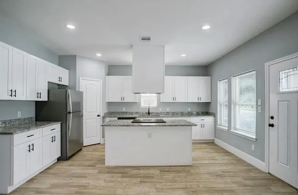 a kitchen with stainless steel appliances granite countertop a stove top oven a refrigerator a sink and dishwasher with white cabinets