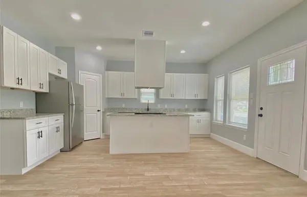 a large kitchen with granite countertop a white stove top oven and white cabinets