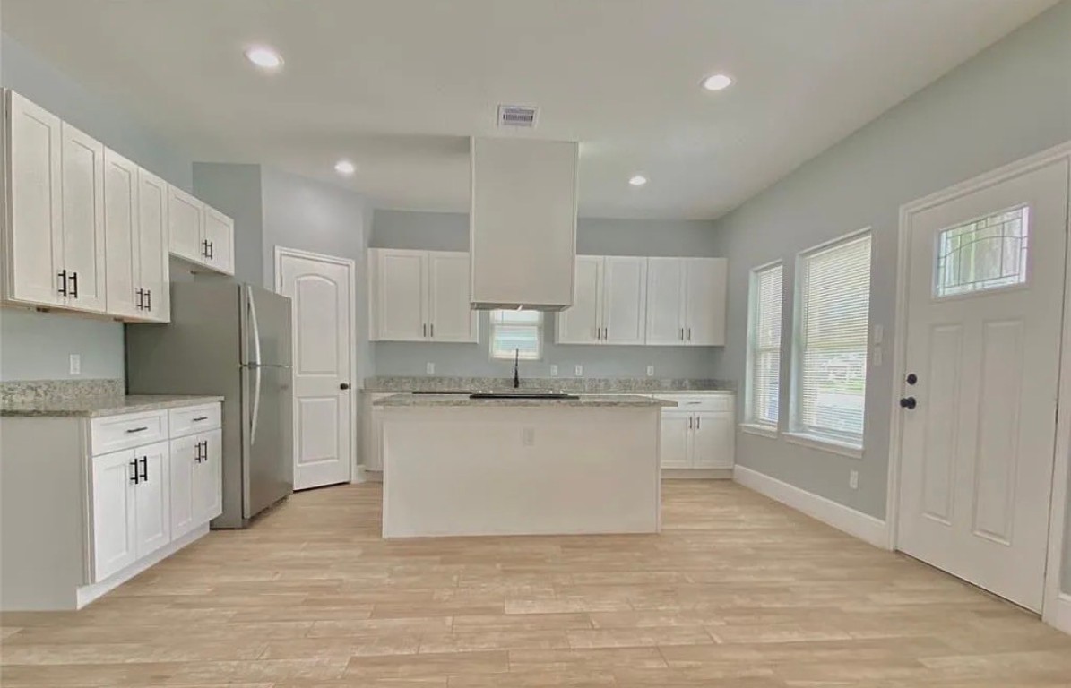5754 Reed Road, Unit B Houston, TX 77033 - Photo 2 of 15 a large kitchen with granite countertop a white stove top oven and white cabinets
