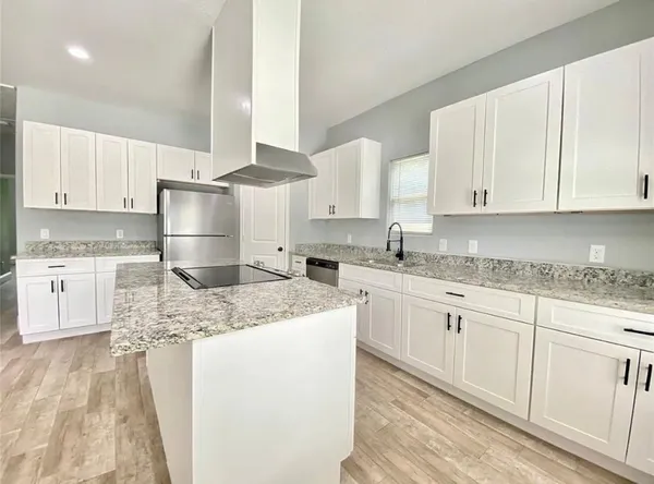 a kitchen with granite countertop white cabinets sink and white stainless steel appliances