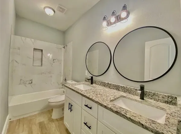 a bathroom with a granite countertop toilet a sink and a mirror