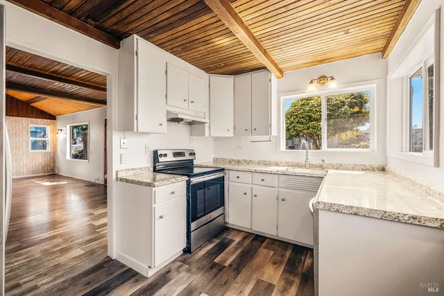 a kitchen with granite countertop white cabinets and white appliances