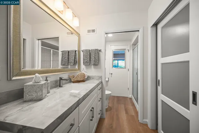 a en suite bathroom with a granite countertop sink and a mirror