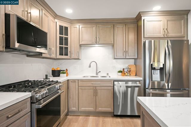 a kitchen with stainless steel appliances granite countertop a stove a sink and a microwave