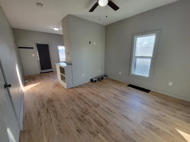 an empty room with wooden floor and windows