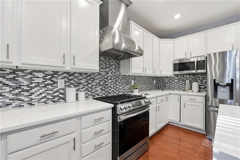 3655 East Paces Walk Atlanta, GA 30326 - Photo 6 of 31 a kitchen with granite countertop white cabinets and stainless steel appliances