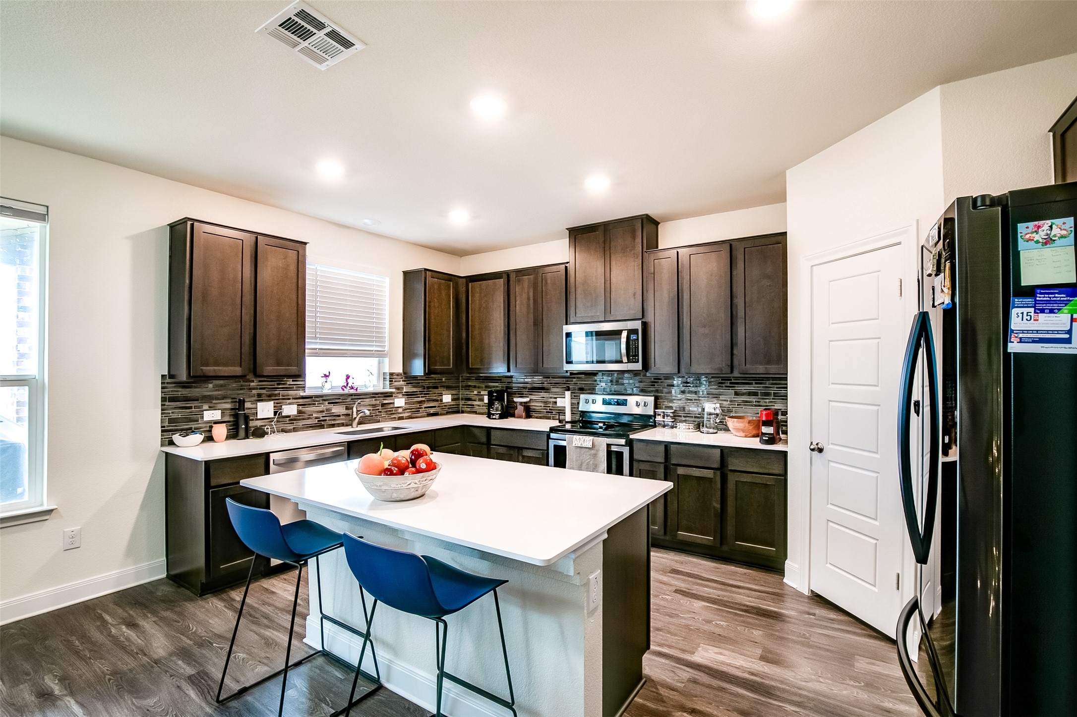 7616 Groundhog Way Austin, TX 78744 - Photo 12 of 34 a kitchen with a stove a refrigerator and a dining table with wooden floor