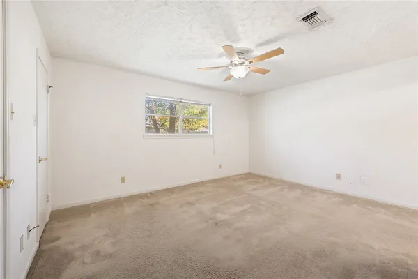 an empty room with windows and fan