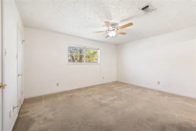 an empty room with windows and fan