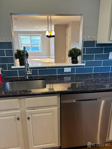 a kitchen with granite countertop white cabinets and stainless steel appliances