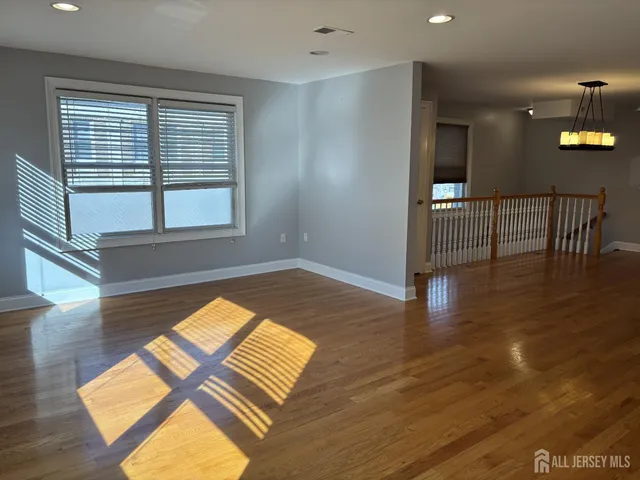 a view of empty room with window and wooden floor