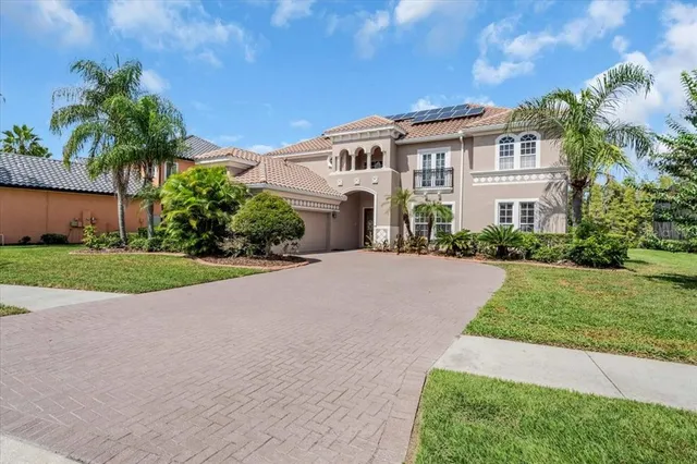 a front view of a house with a garden and palm tree