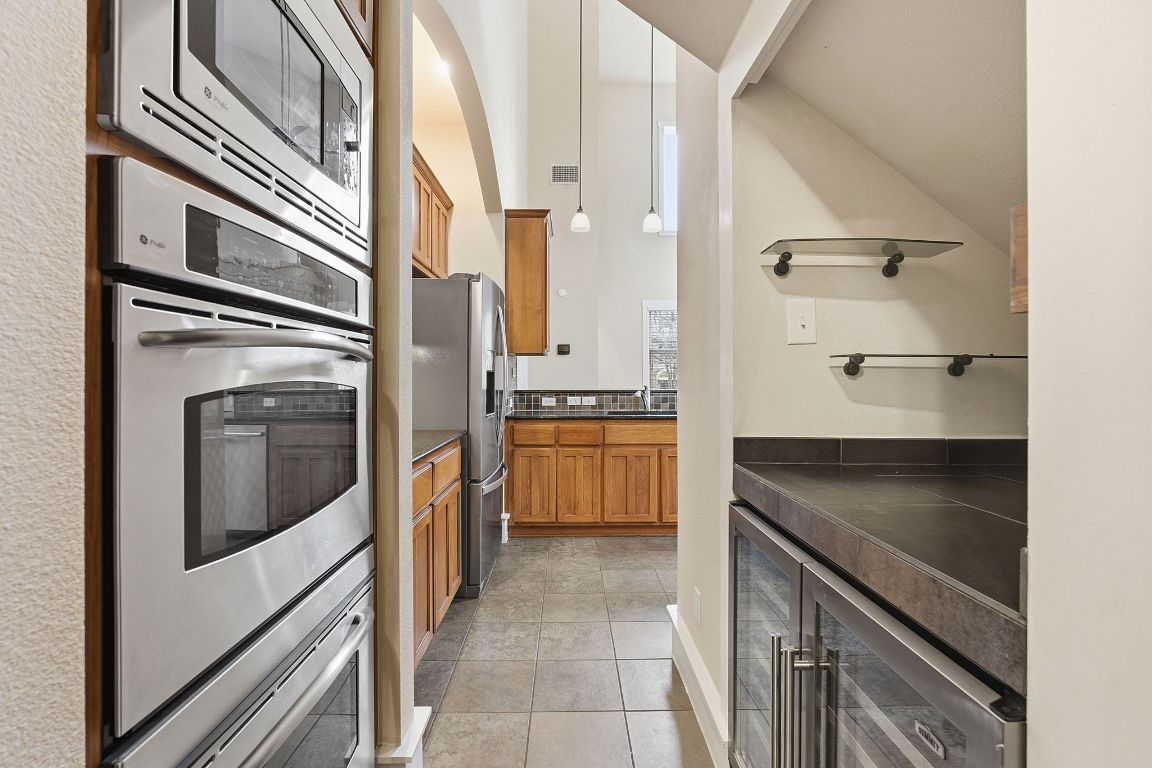 2506 Enfield Road, Unit B Austin, TX 78703 - Photo 13 of 40 Kitchen featuring dark countertops, brown cabinets, wine cooler, appliances with stainless steel finishes, and hanging light fixtures