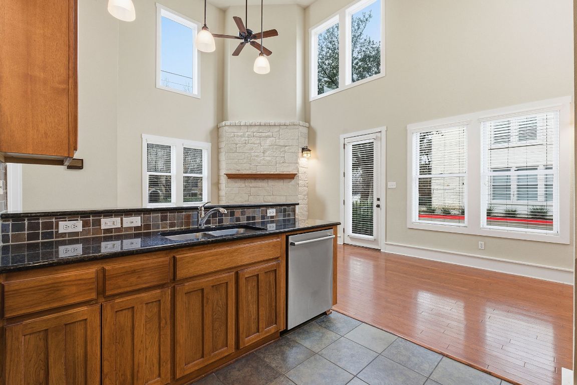 2506 Enfield Road, Unit B Austin, TX 78703 - Photo 14 of 40 Kitchen with brown cabinetry, dark tile patterned floors, dark stone countertops, stainless steel dishwasher, and backsplash