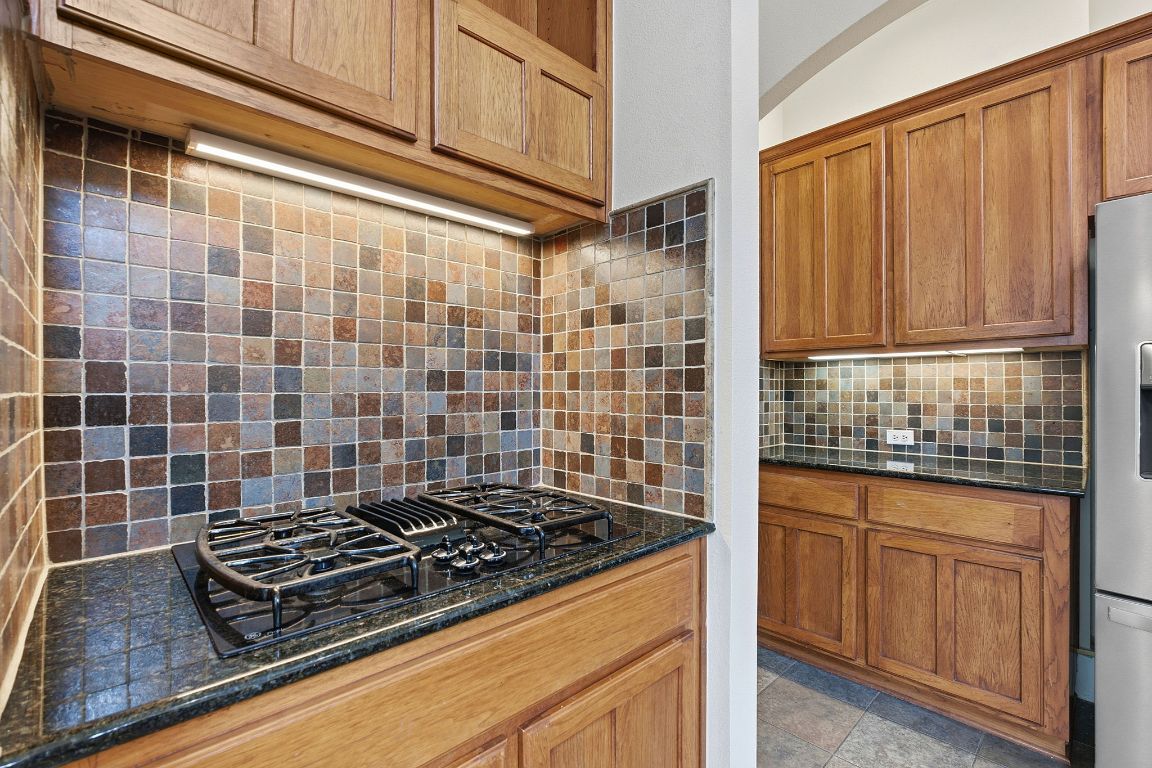 2506 Enfield Road, Unit B Austin, TX 78703 - Photo 18 of 40 Kitchen with dark stone counters, brown cabinets, tasteful backsplash, and black gas cooktop