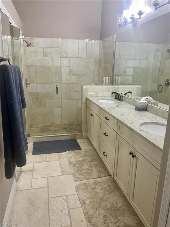 9035 Spring Run Boulevard Estero, FL 34135 - Photo 5 of 9 Full bathroom with double vanity, a stall shower, and stone tile flooring