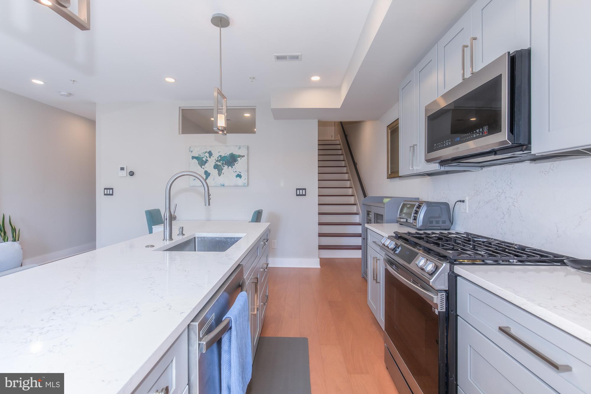1444 Harvard Street Northwest, Unit 302 Washington, DC 20009 - Photo 15 of 50 a kitchen with kitchen island stainless steel appliances a sink a stove and cabinets