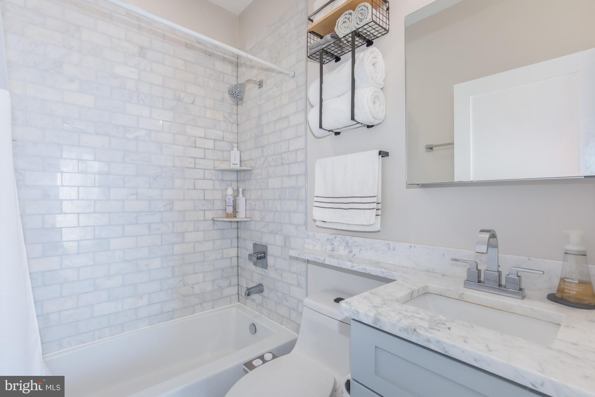 1444 Harvard Street Northwest, Unit 302 Washington, DC 20009 - Photo 35 of 50 a bathroom with a granite countertop sink a mirror and shower