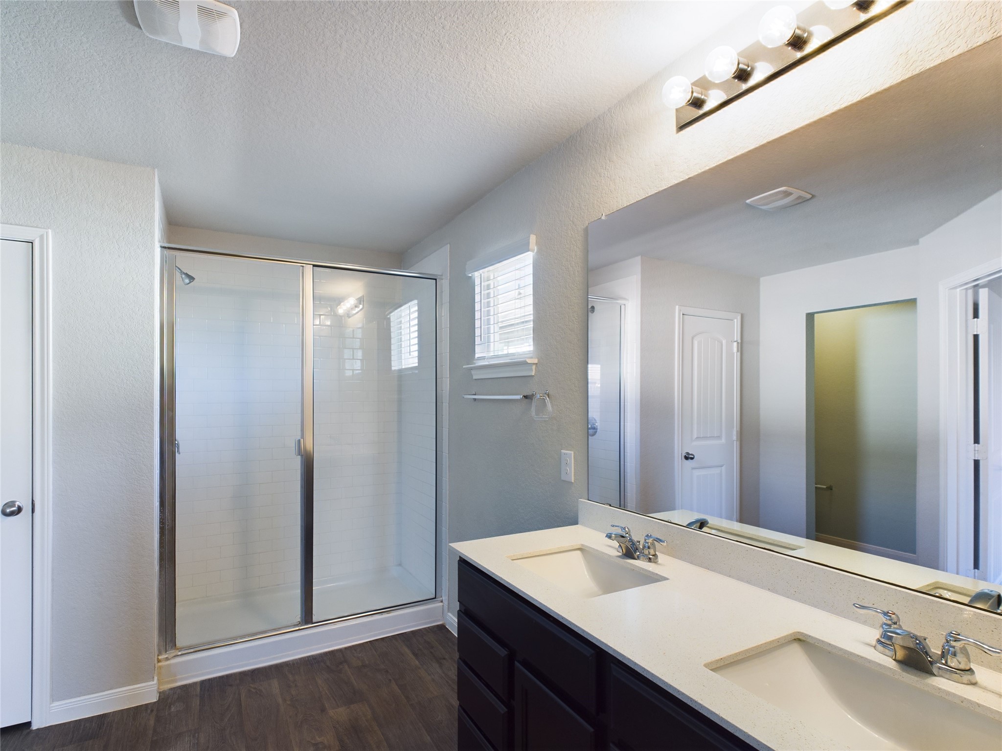 114 Cranbrook Lane Hutto, TX 78634 - Photo 34 of 38 Bathroom with a textured ceiling, wood-type flooring, walk in shower, and vanity