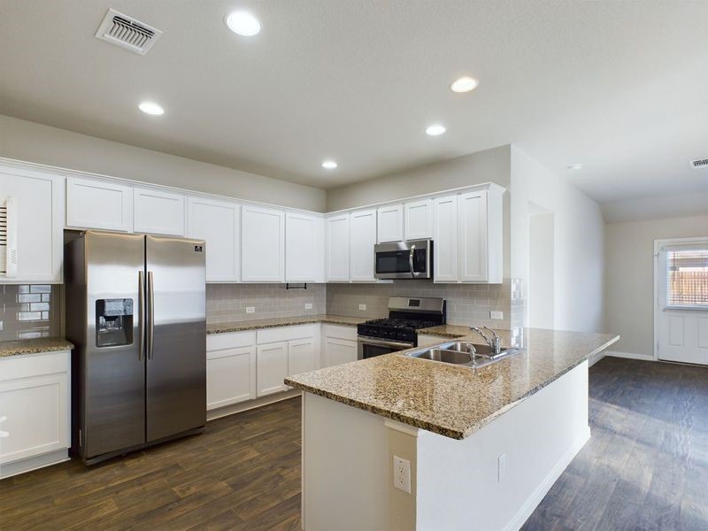 114 Cranbrook Lane Hutto, TX 78634 - Photo 4 of 38 Kitchen featuring light stone countertops, white cabinets, appliances with stainless steel finishes, sink, and kitchen peninsula