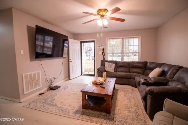 a living room with furniture a flat screen tv and a window