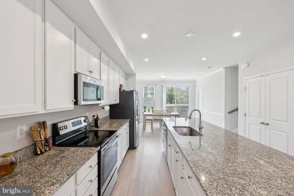 a large kitchen with stainless steel appliances granite countertop a lot of counter space a sink and dishwasher a stove top oven with wooden floor