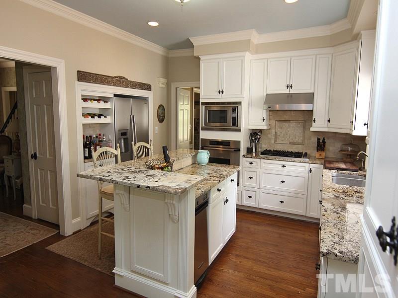 2305 Tyson Street Raleigh, NC 27612 - Photo 9 of 25 a kitchen with stainless steel appliances granite countertop a stove top oven a refrigerator and white cabinets with wooden floor