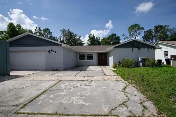 a white house with a yard and a large parking space