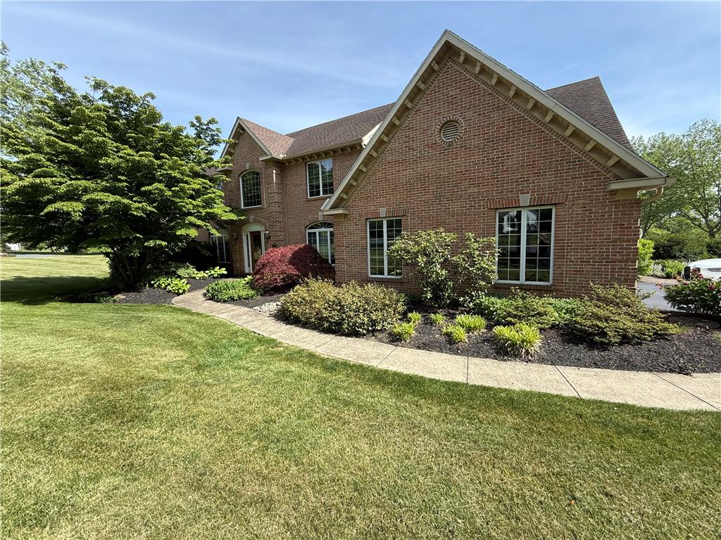 A well-maintained brick exterior home boasts lush landscaping and a welcoming sidewalk.