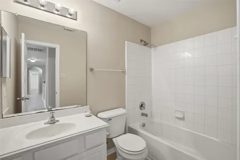 a bathroom with a bathtub shower sink mirror vanity and toilet