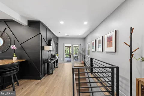 a view of a hallway with wooden floor and a bathroom