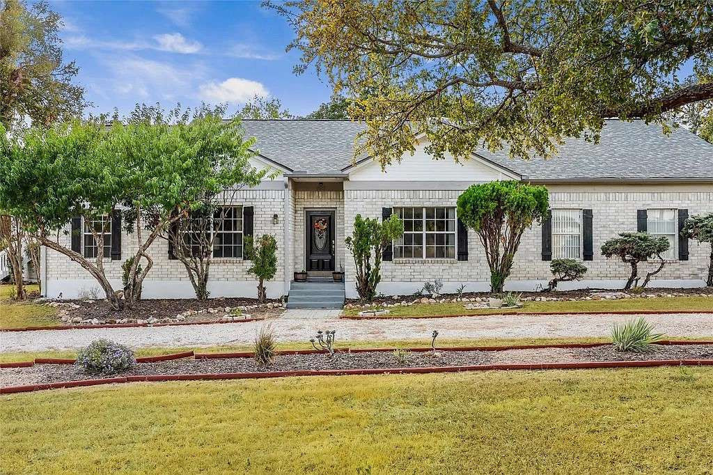 View of front of house with brick siding, a shingled roof, and a front yard