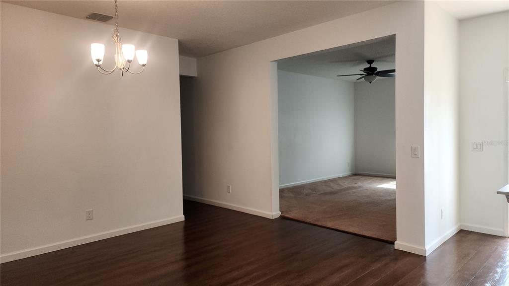3230 Stratton Circle Kissimmee, FL 34744 - Photo 4 of 28 an empty room with wooden floor and a chandelier