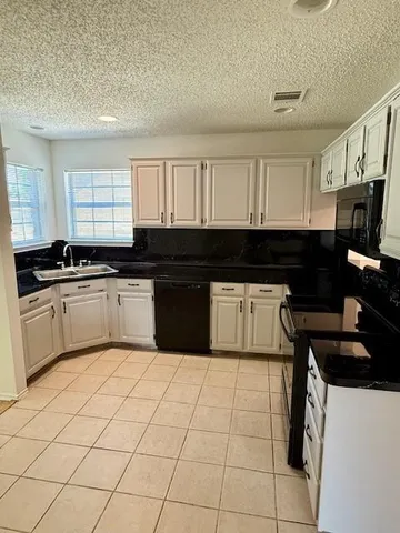 a kitchen with a sink a stove top oven and cabinets