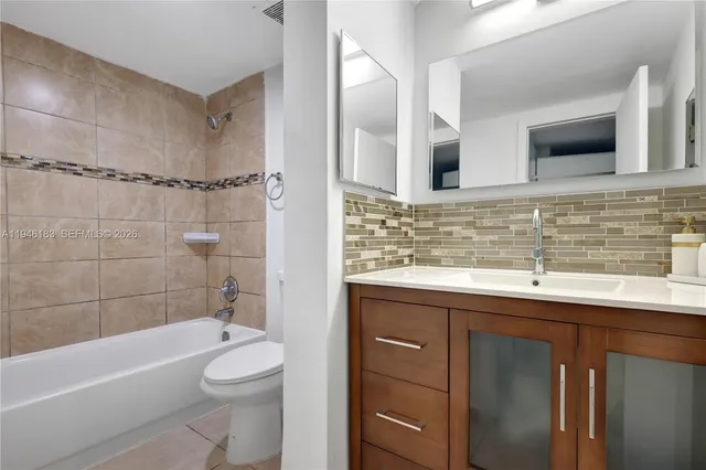 a bathroom with a sink a toilet a mirror a bathtub and shower