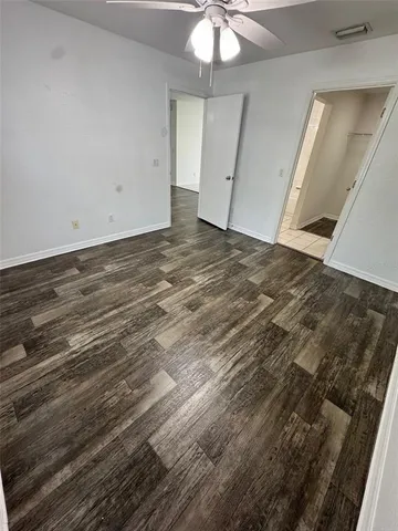 en empty room with wooden floor and fan