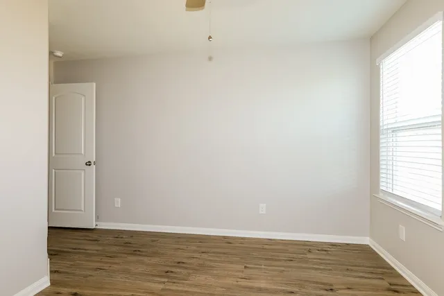 a view of an empty room with wooden floor and a window