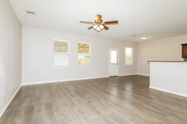 a view of an empty room with wooden floor and a window
