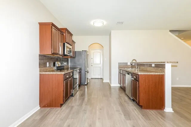 a kitchen with stainless steel appliances granite countertop a refrigerator a stove and a wooden floors