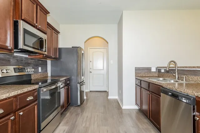 a kitchen with stainless steel appliances granite countertop a stove a sink and a microwave