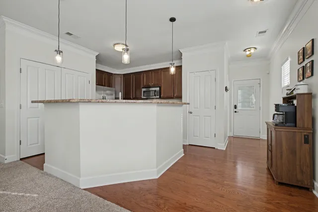 a view of a kitchen with stainless steel appliances a refrigerator and wooden floor