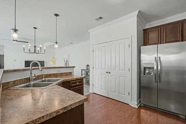a kitchen with stainless steel appliances granite countertop a sink a refrigerator and a wooden floor