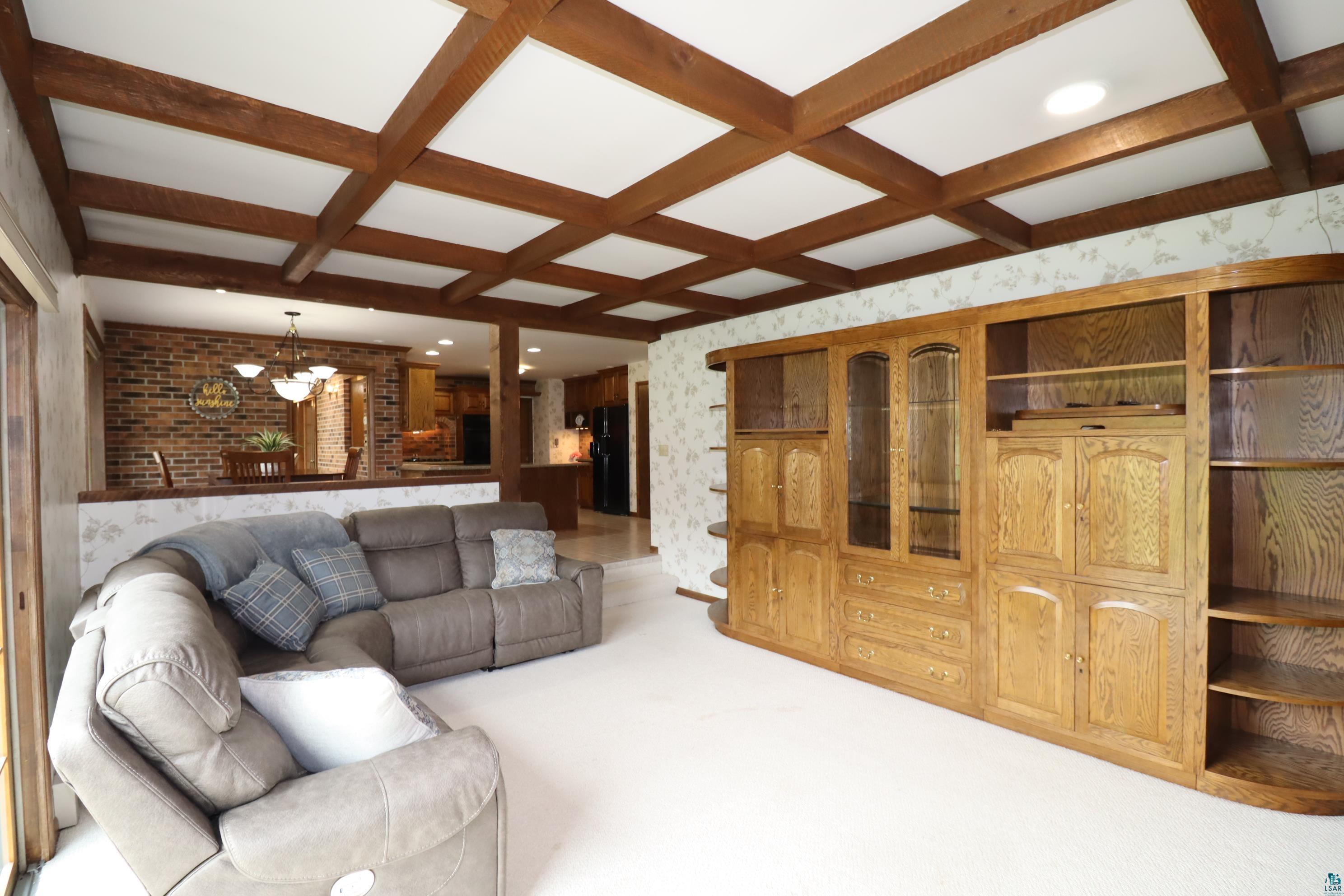 200 Maple Ridge Ashland, WI 54806 - Photo 5 of 40 Family room with carpet flooring, a brick fireplace, beamed ceiling, and coffered ceiling.