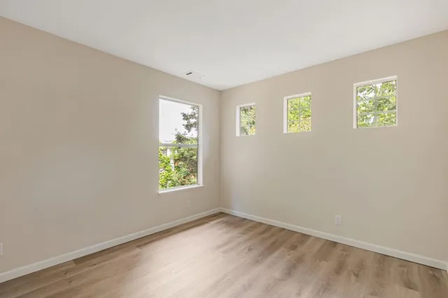 an empty room with wooden floor windows and closet