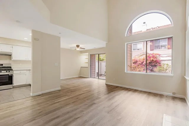a view of an empty room with wooden floor fireplace and a window