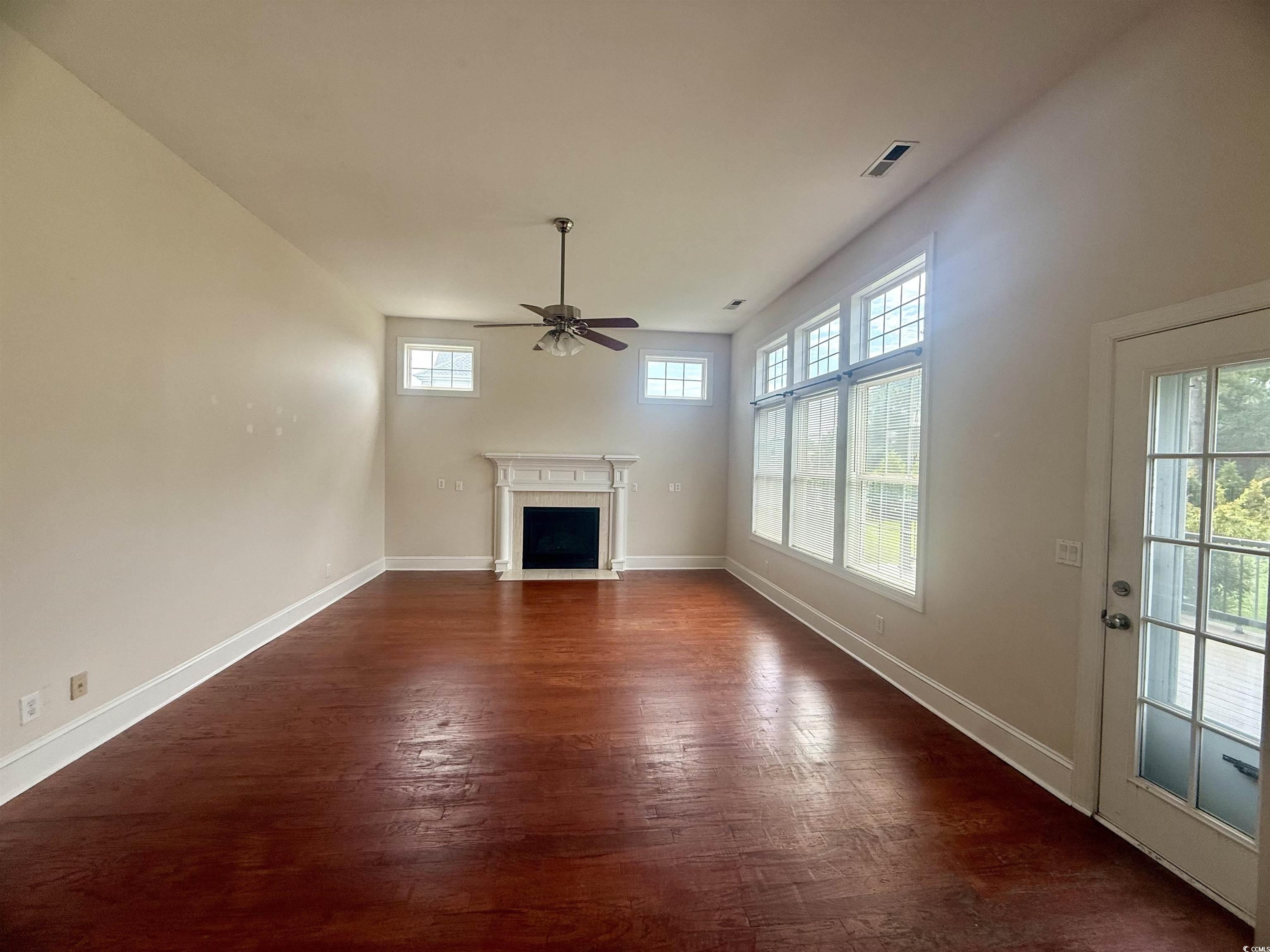 3848 Waterford Drive Myrtle Beach, SC 29577 - Photo 5 of 12 Unfurnished living room featuring dark wood-style flooring, a fireplace with flush hearth, and a ceiling fan